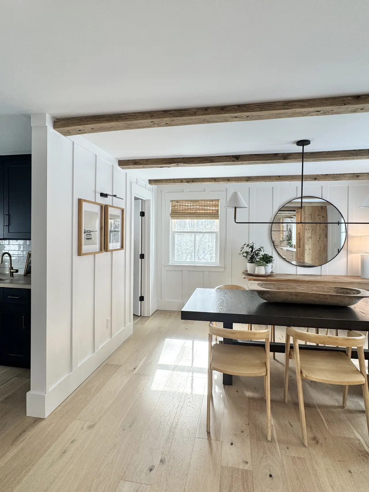 An open kitchen and dining space with white shiplap and wide-plank floors