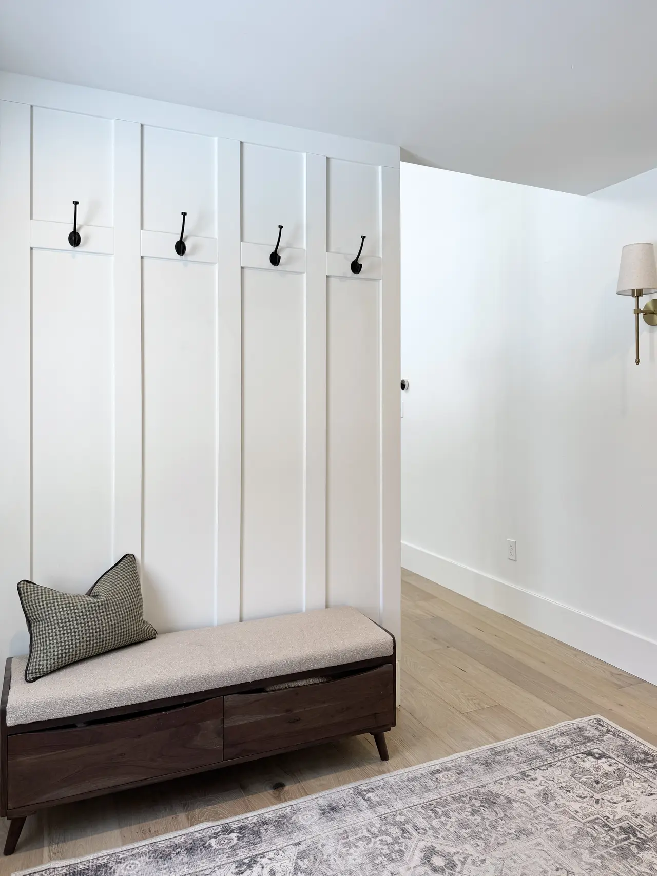 A board-and-batten entry with a bench, rug, and hooks