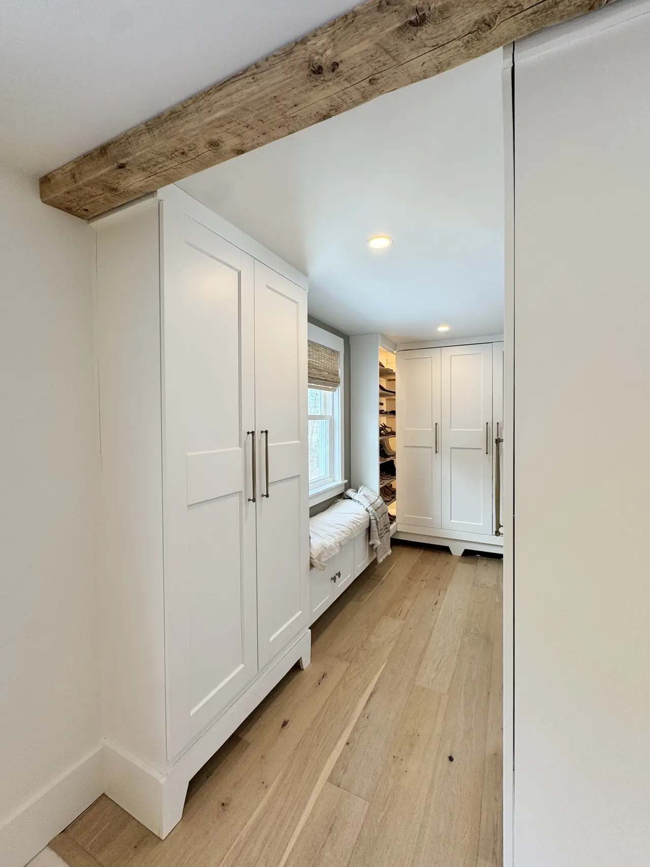 A hallway of built-in cabinetry beneath a wood beam