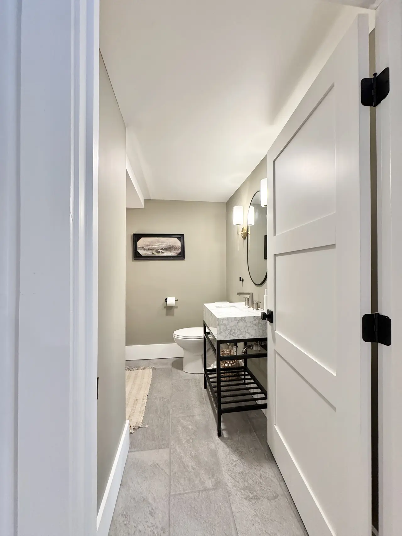 A powder room with a paneled door and slim vanity