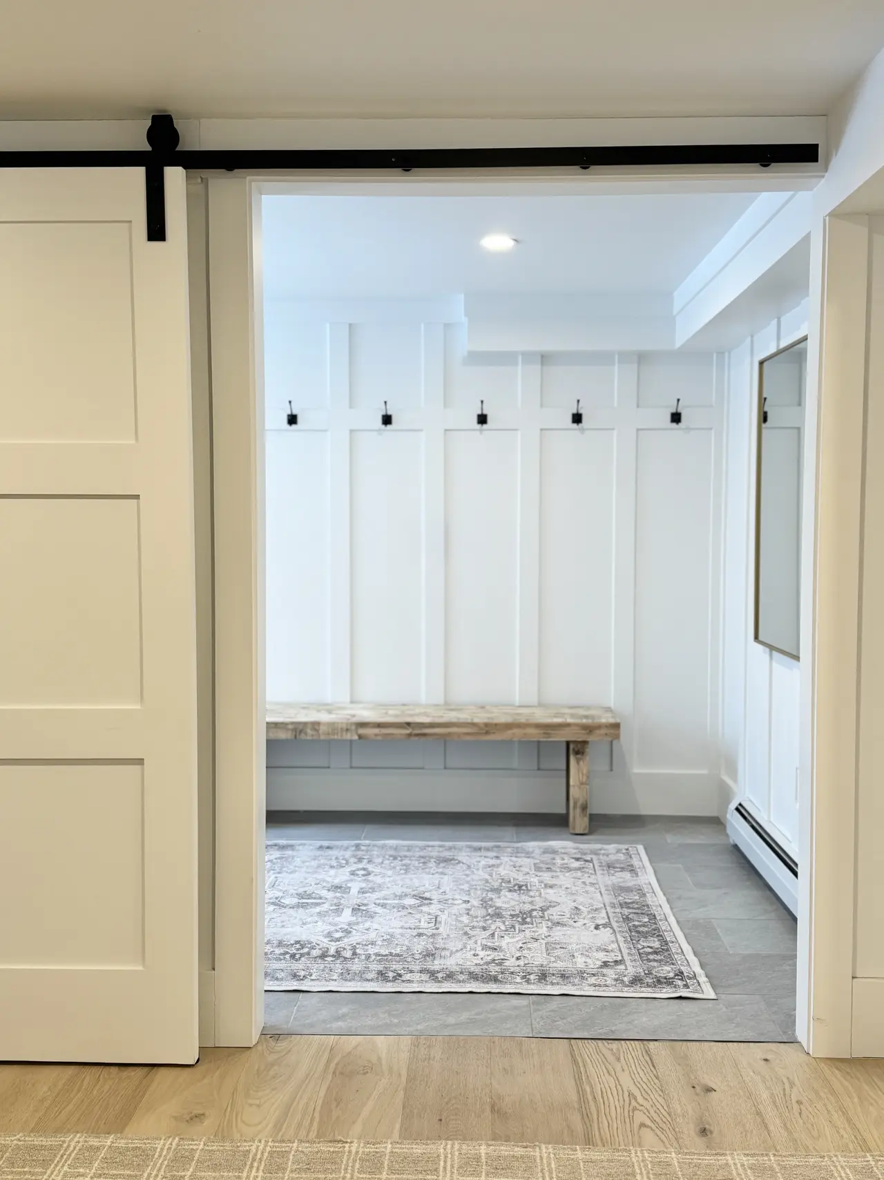 A mudroom with a barn door, bench, and board-and-batten