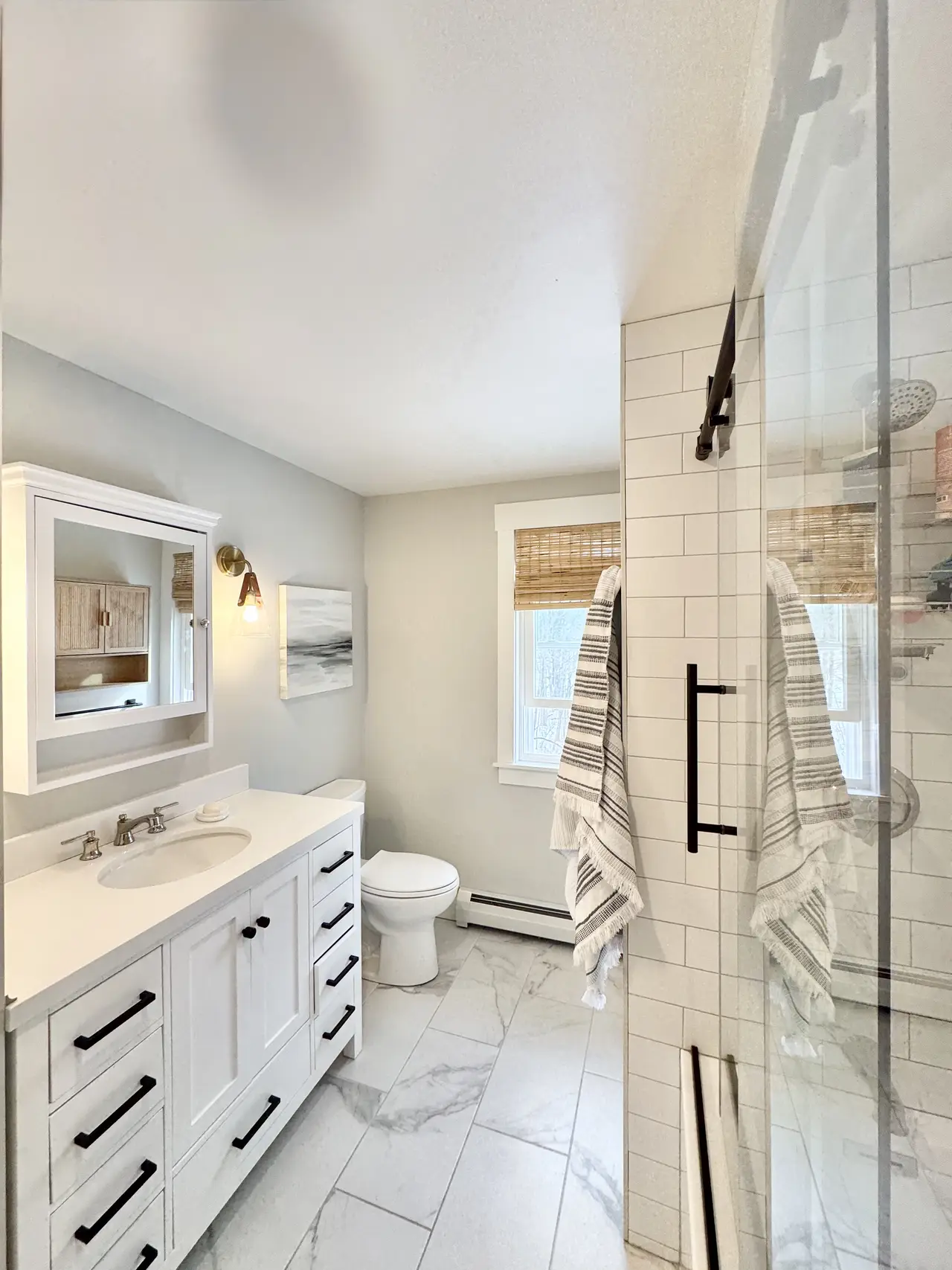 A white bath with a glass walk-in shower and marble floor