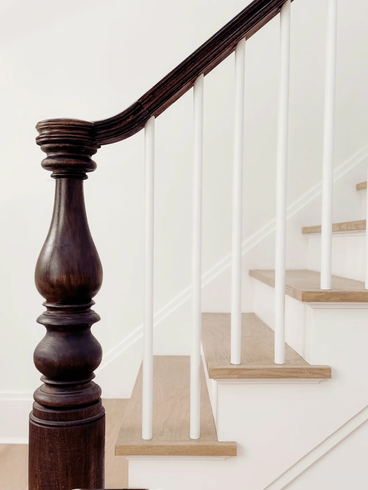 A turned newel post and white staircase in a designed home