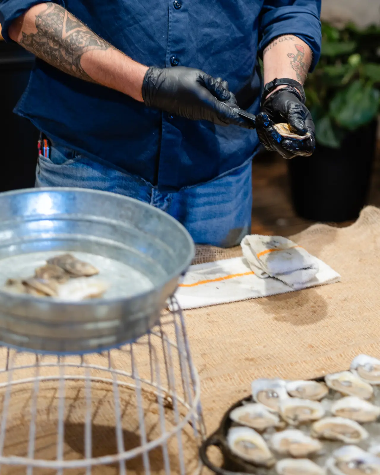 A maker shucking oysters over a metal tin