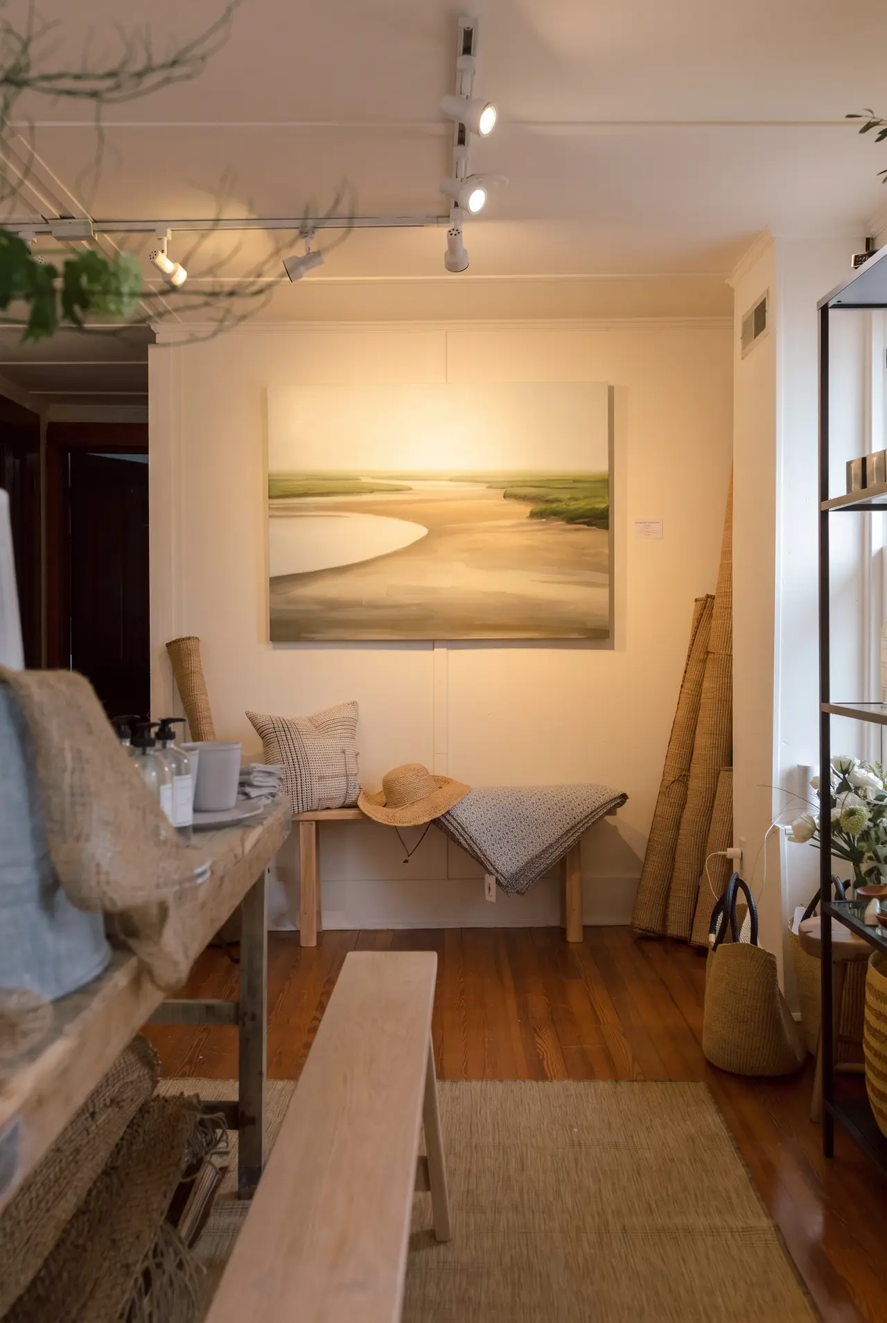 Original art above a bench of textiles in the Rehoboth shop